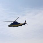 blue and yellow helicopter in flight against sky