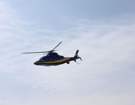blue and yellow helicopter in flight against sky